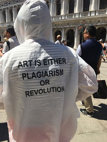 someone seen from behind wearing a white hoodie with the text ART IS EITHER PLAGIARISM OR REVOLUTION