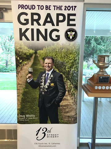 standing display banner with picture and text: PROUD TO BE THE 2017 GRAPE KING [picture] Doug Whitty, 13th Street Winery